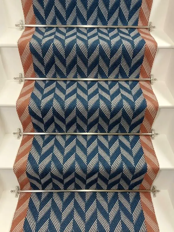 Blue Herringbone stair runner with orange woven border on white stairs