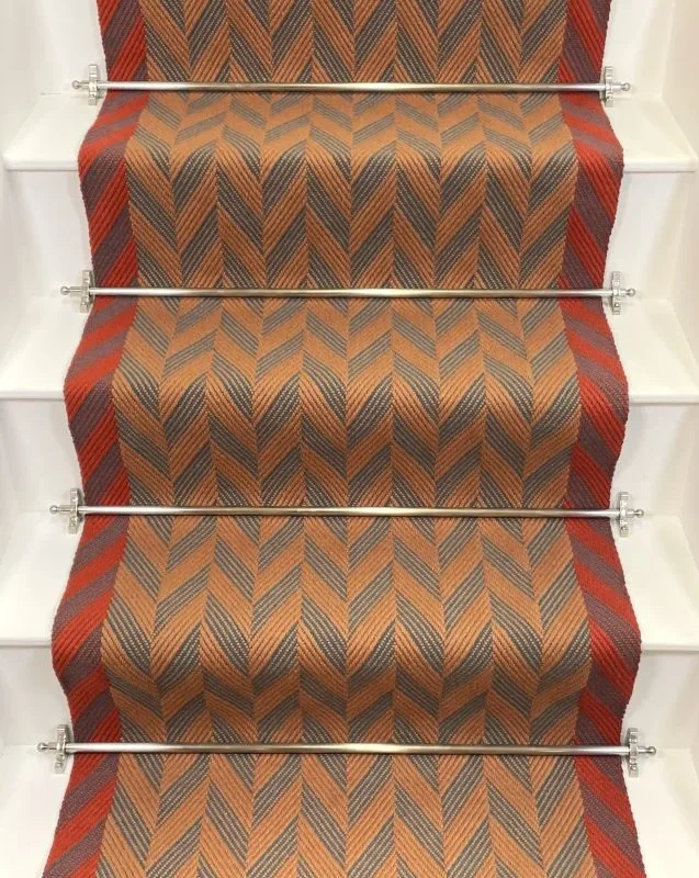 Cinnamon and Spruce Herringbone stair runner with vibrant red woven border on white stairs