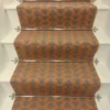 Cinnamon-coloured stair runner with green triangle pattern on white wooden stairs