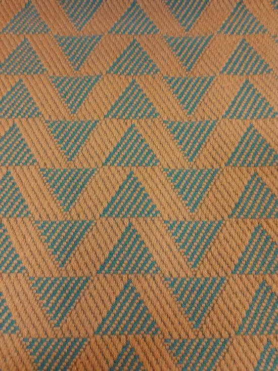 Cinnamon-coloured stair runner with green triangle pattern on white wooden stairs