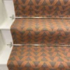 Cinnamon-coloured stair runner with green triangle pattern on white wooden stairs