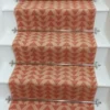 Light pink stair runner with triangle pattern on white wooden stairs