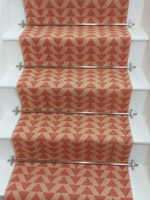 Light pink stair runner with triangle pattern on white wooden stairs