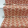 Light pink stair runner with triangle pattern on white wooden stairs