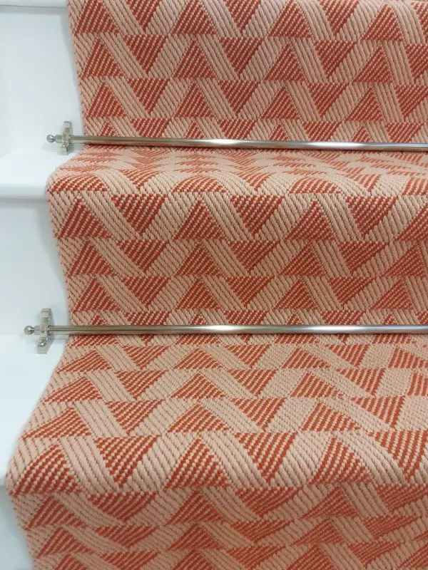 Light pink stair runner with triangle pattern on white wooden stairs